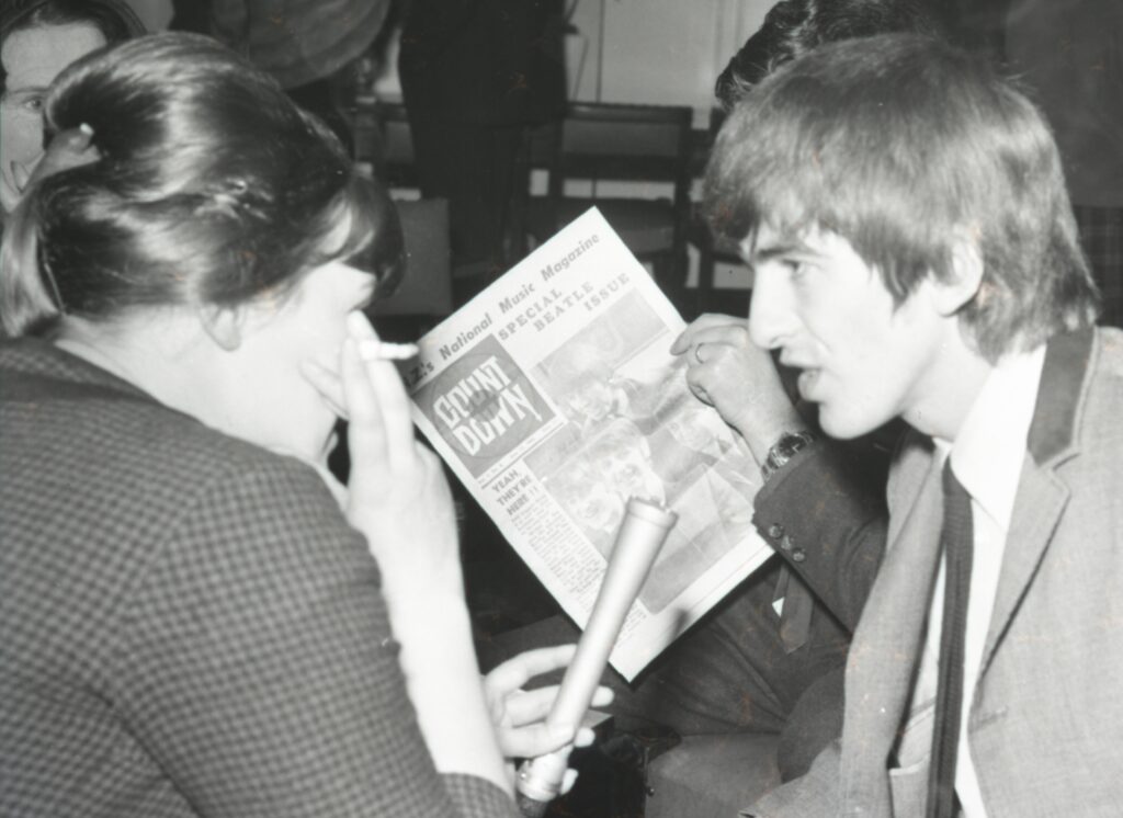 George Harrison and areporter sit down to talk during The Beatles visit to Aotearoa in June 1964