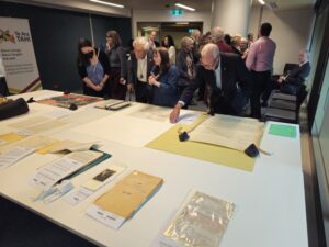 People looking at archival items on display on a white table