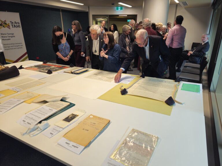 People looking at archival items on display on a white table